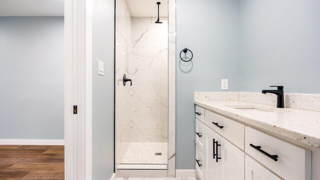 bathroom with vanity, a tile shower, and wood-type flooring