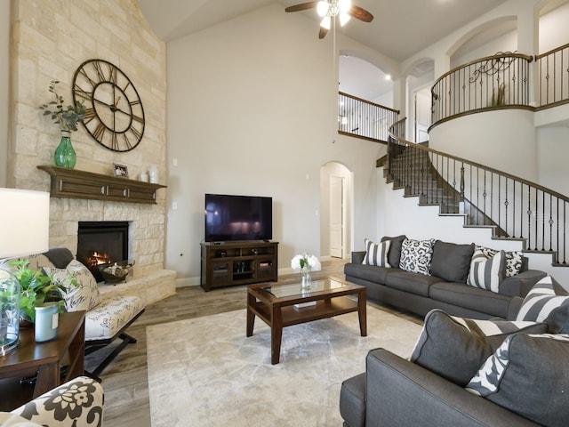 living room featuring ceiling fan, high vaulted ceiling, light wood-type flooring, and a fireplace