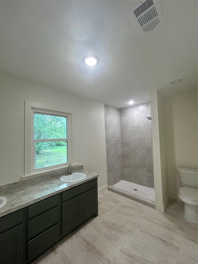 bathroom with vanity, toilet, and tiled shower