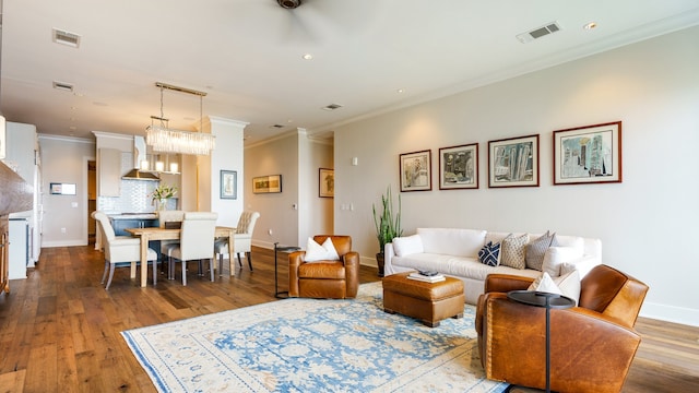 living room featuring a chandelier, hardwood / wood-style flooring, and ornamental molding