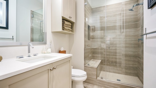 bathroom featuring vanity, a shower with door, and toilet