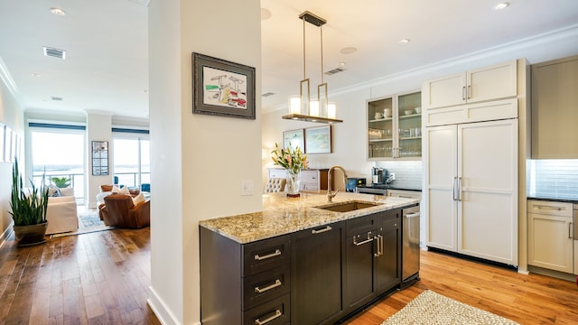 kitchen featuring paneled built in fridge, light hardwood / wood-style floors, decorative backsplash, sink, and ornamental molding