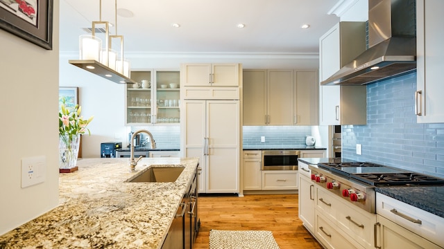 kitchen featuring light hardwood / wood-style flooring, tasteful backsplash, paneled built in fridge, light stone countertops, and wall chimney exhaust hood