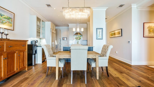 dining area featuring crown molding, hardwood / wood-style flooring, and a notable chandelier