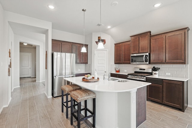 kitchen featuring stainless steel appliances, sink, tasteful backsplash, and a center island with sink