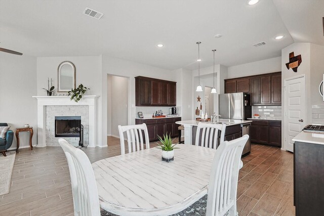 dining room with a stone fireplace, sink, and vaulted ceiling