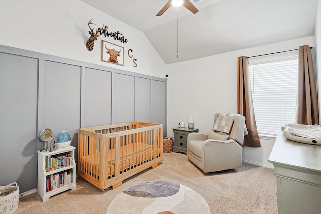 carpeted bedroom featuring a crib, ceiling fan, and lofted ceiling