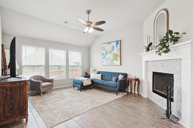 living room featuring a fireplace, light wood-type flooring, ceiling fan, and lofted ceiling