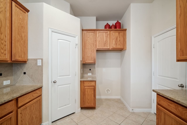 kitchen with light stone counters, light tile patterned flooring, and decorative backsplash