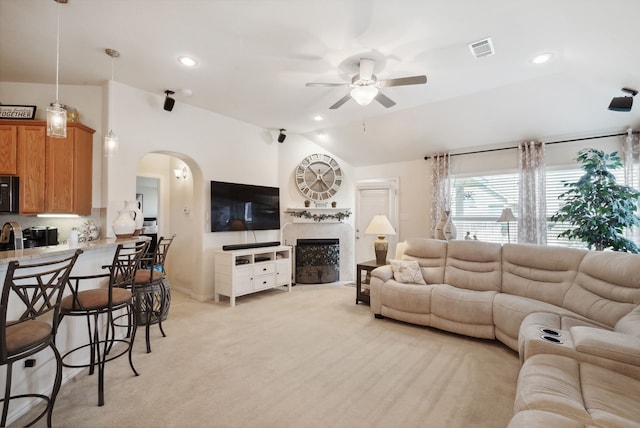 living room featuring light colored carpet, vaulted ceiling, and ceiling fan