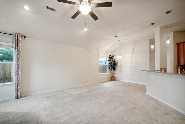 unfurnished living room with light colored carpet, vaulted ceiling, and ceiling fan