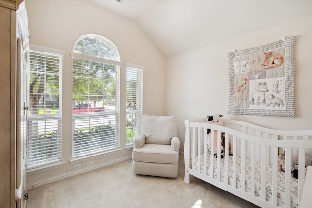 carpeted bedroom with a crib, vaulted ceiling, and multiple windows