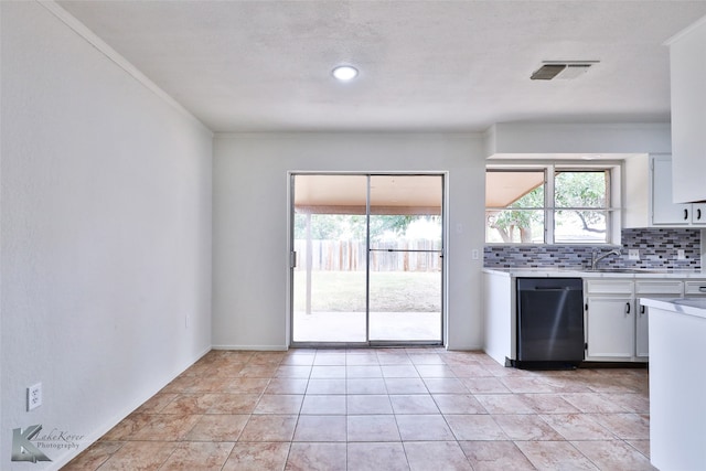 kitchen featuring light tile patterned flooring, white cabinetry, crown molding, tasteful backsplash, and dishwasher