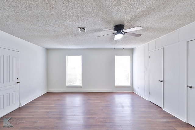 unfurnished bedroom with multiple windows, a textured ceiling, hardwood / wood-style flooring, and ceiling fan