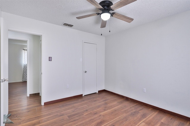 unfurnished bedroom with a textured ceiling, hardwood / wood-style floors, and ceiling fan