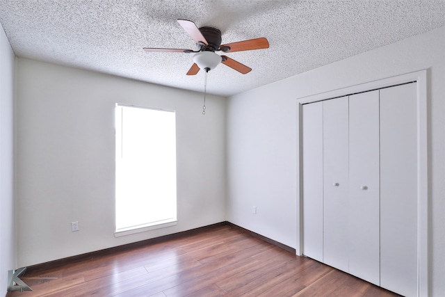 unfurnished bedroom with hardwood / wood-style flooring, multiple windows, and ceiling fan