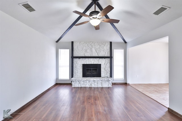 unfurnished living room with plenty of natural light, dark hardwood / wood-style floors, ceiling fan, and vaulted ceiling with beams