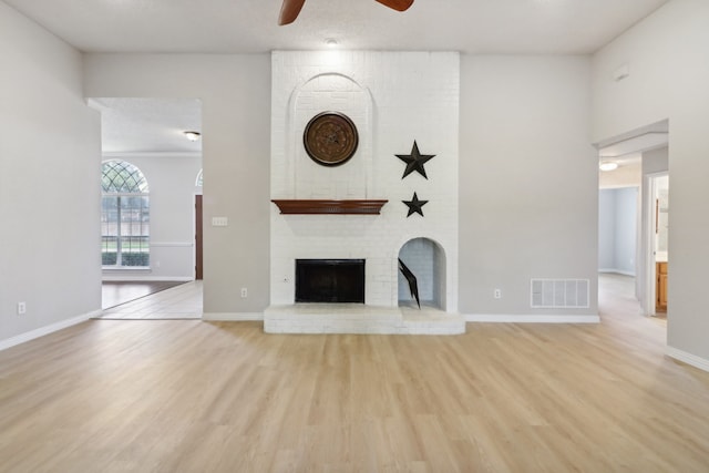 unfurnished living room with brick wall, light wood-type flooring, and ceiling fan