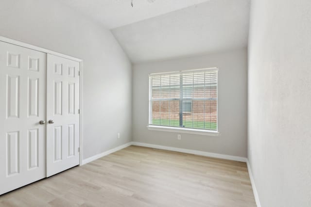 unfurnished bedroom featuring a closet, lofted ceiling, and light hardwood / wood-style floors