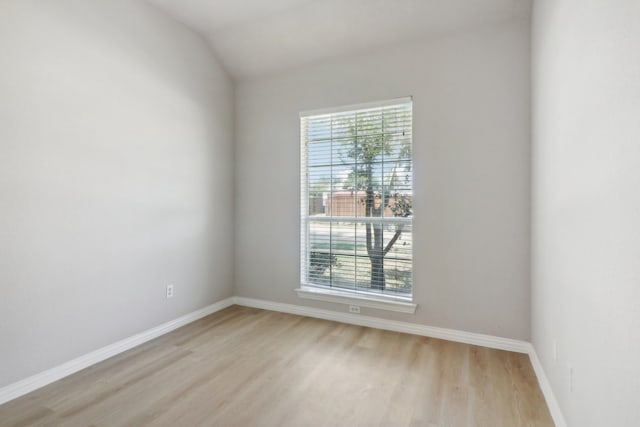 spare room featuring light hardwood / wood-style floors, a healthy amount of sunlight, and vaulted ceiling