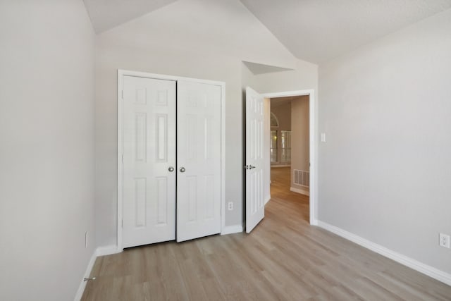 unfurnished bedroom with light hardwood / wood-style floors, a closet, and lofted ceiling