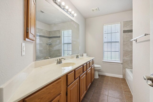 full bathroom with tile patterned floors, vanity, tiled shower / bath combo, and toilet