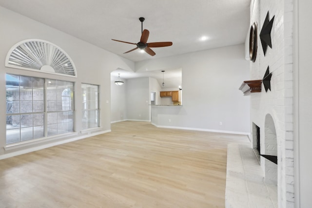 unfurnished living room featuring a fireplace, light hardwood / wood-style floors, and ceiling fan