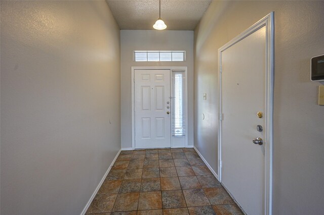 entrance foyer featuring dark tile patterned flooring and a textured ceiling