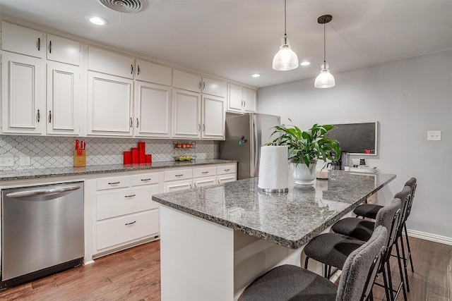 kitchen featuring pendant lighting, a breakfast bar area, appliances with stainless steel finishes, white cabinetry, and a kitchen island