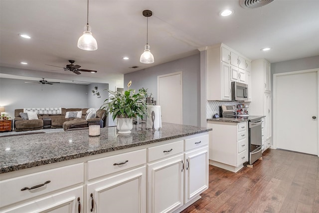 kitchen featuring white cabinetry, stainless steel appliances, dark hardwood / wood-style flooring, and dark stone counters