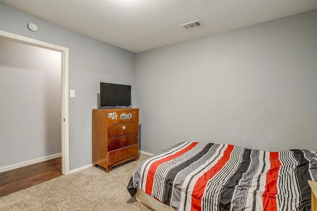 bedroom featuring light carpet and a textured ceiling