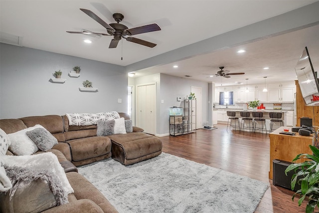 living room featuring dark wood-type flooring and ceiling fan