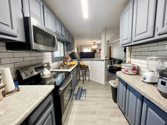 kitchen with light hardwood / wood-style floors, appliances with stainless steel finishes, tasteful backsplash, and sink