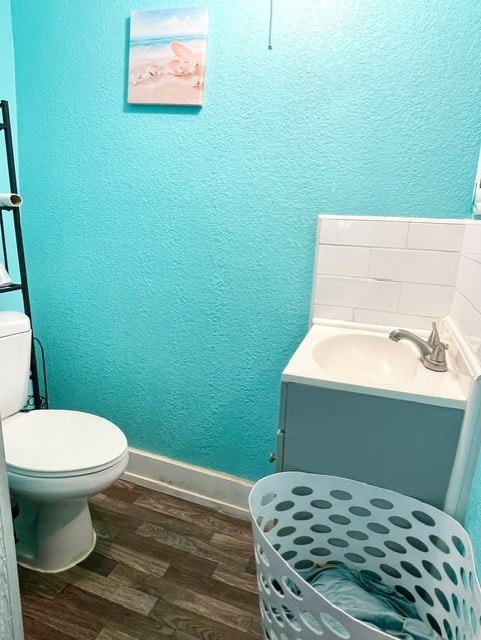 bathroom with hardwood / wood-style flooring, toilet, and vanity