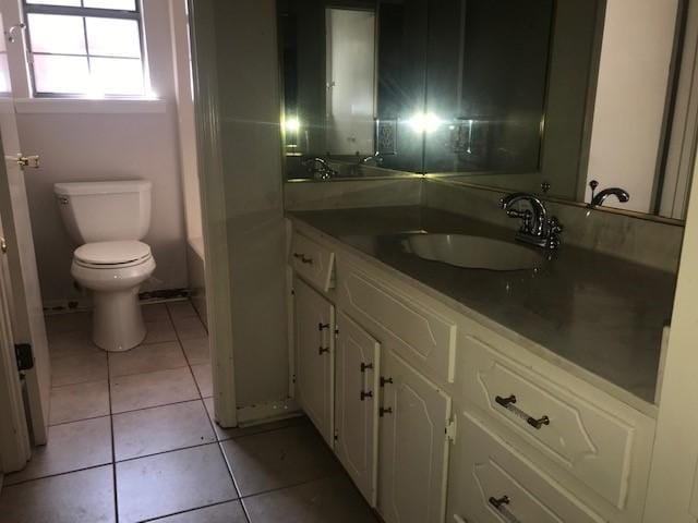 bathroom featuring tile patterned flooring, vanity, a bathing tub, and toilet