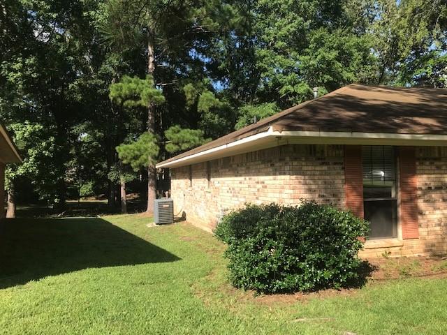 view of side of property with cooling unit and a yard