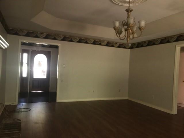 foyer with an inviting chandelier, a tray ceiling, and hardwood / wood-style flooring