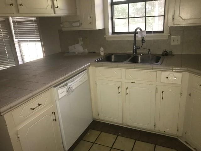 kitchen featuring tile countertops, white dishwasher, sink, and white cabinets