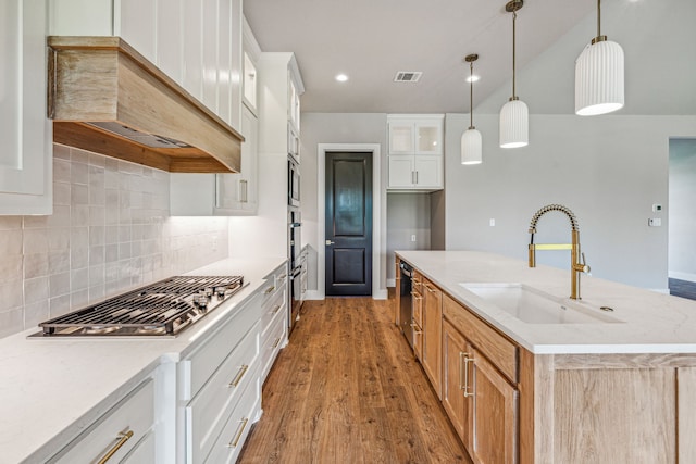 kitchen featuring white cabinetry, hardwood / wood-style floors, sink, custom range hood, and backsplash