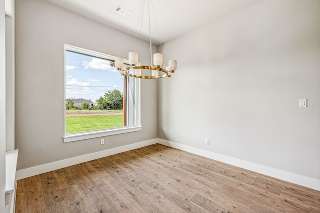 unfurnished room with light hardwood / wood-style floors, a notable chandelier, and a wealth of natural light