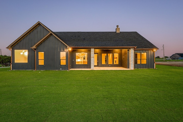 back house at dusk featuring a yard