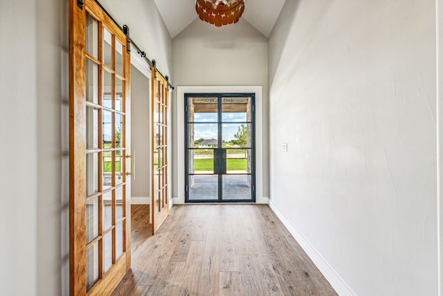 doorway to outside with a barn door, lofted ceiling, hardwood / wood-style flooring, and french doors