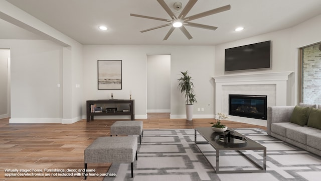 living room with hardwood / wood-style flooring, ceiling fan, and a premium fireplace