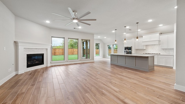 kitchen featuring pendant lighting, a kitchen island with sink, ceiling fan, light wood-type flooring, and white cabinetry