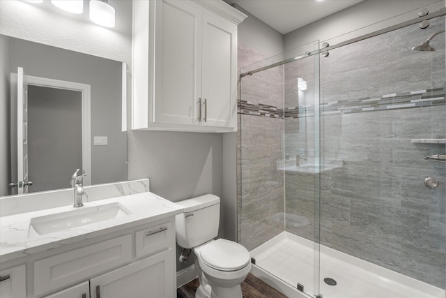 bathroom featuring vanity, an enclosed shower, wood-type flooring, and toilet