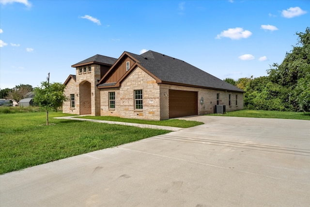 view of front of property featuring a garage, central air condition unit, and a front yard