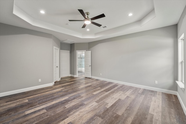 empty room featuring hardwood / wood-style floors, ceiling fan, and a raised ceiling