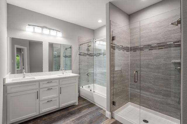 bathroom featuring wood-type flooring, double sink vanity, and combined bath / shower with glass door