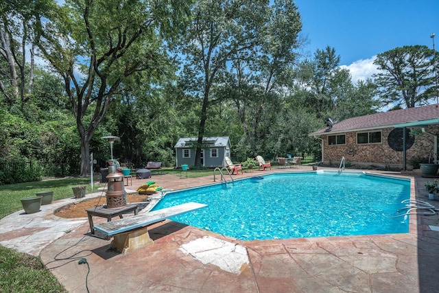 view of swimming pool featuring a storage shed, a diving board, and a patio area