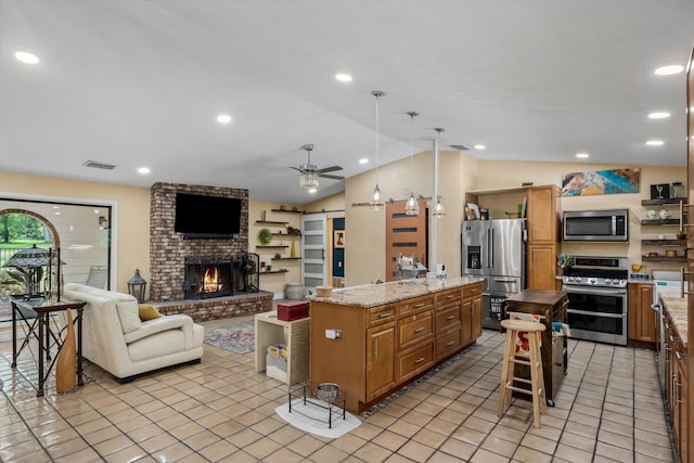 kitchen with hanging light fixtures, stainless steel appliances, a barn door, and a kitchen island